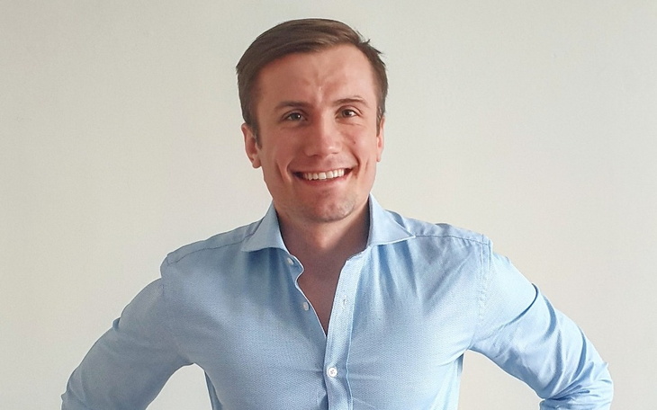 Mężczyzna w niebieskiej koszuli, uśmiechający się do kamery.