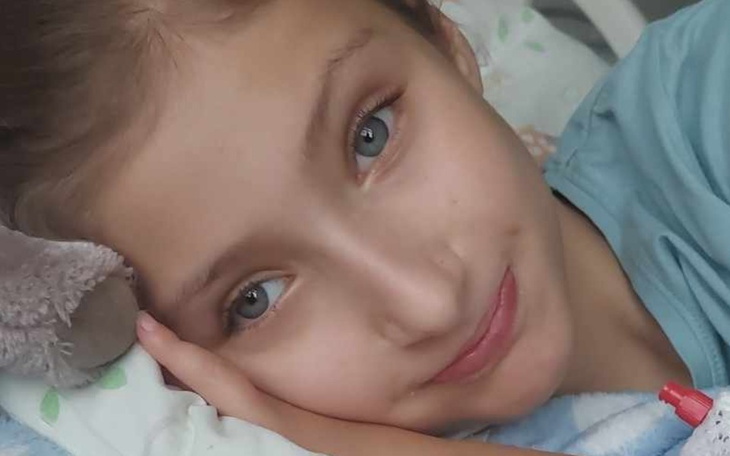 Dziewczynka leżąca na łóżku, z ręką pod głową.