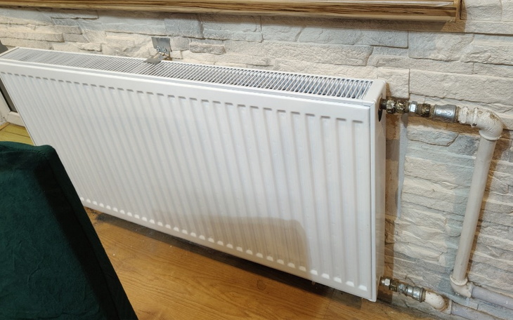 Nowoczesny grzejnik zamontowany na ścianie w jasnym wnętrzu.