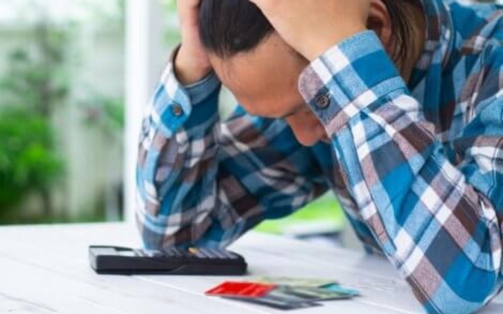 Zmartwiony mężczyzna z kalkulatorem i kartami kredytowymi.