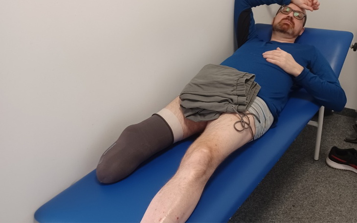 Mężczyzna leżący na stole, z nogą w opatrunku.