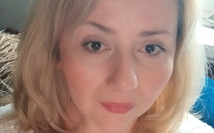 Portret kobiety z blond włosami, uśmiechającej się do kamery.