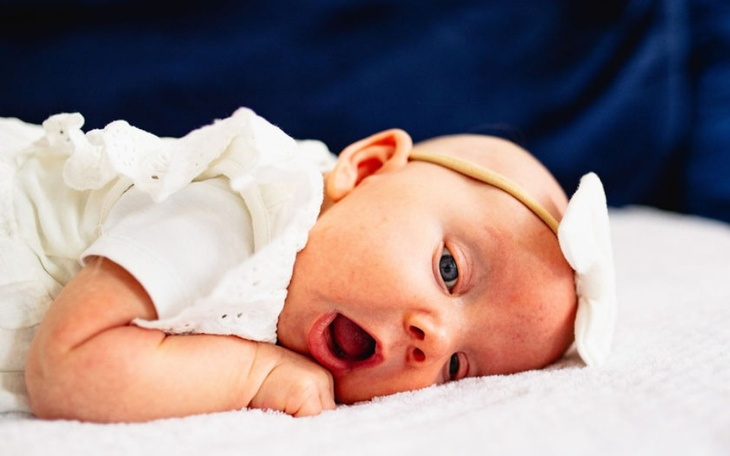 Małe dziecko leży na podłodze, uśmiechając się szeroko.