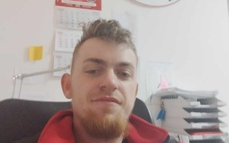 Mężczyzna z brodą siedzący w biurze, uśmiechający się do kamery.