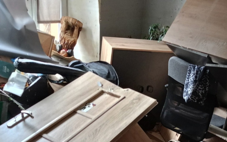 Zniszczone wnętrze z przewróconymi meblami.