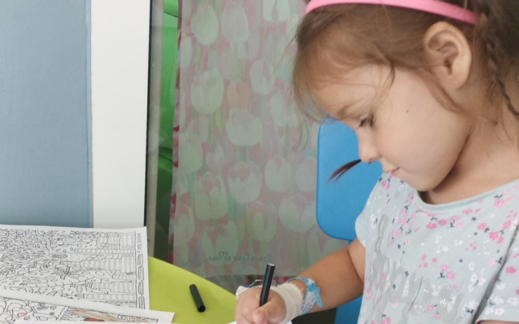 Mała dziewczynka kolorująca obrazek przy stole.