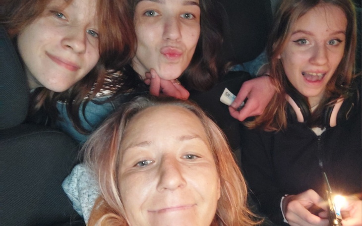 Grupa czterech przyjaciół pozujących do zdjęcia w samochodzie.