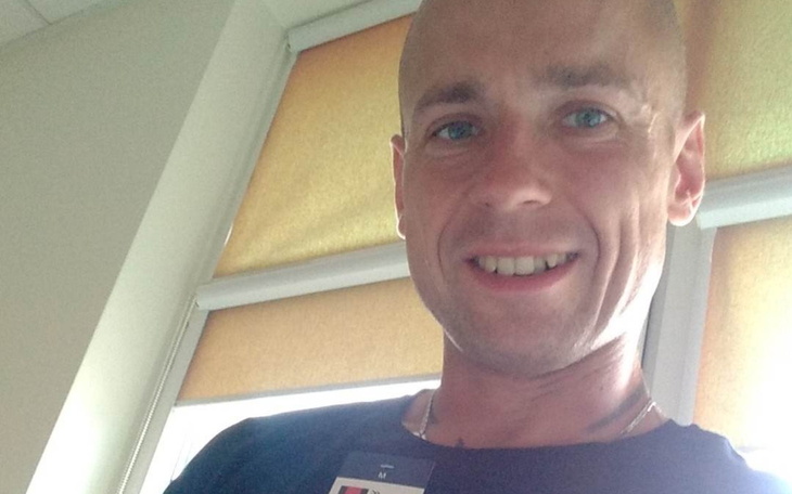 Mężczyzna uśmiechający się do kamery w jasnym pomieszczeniu.