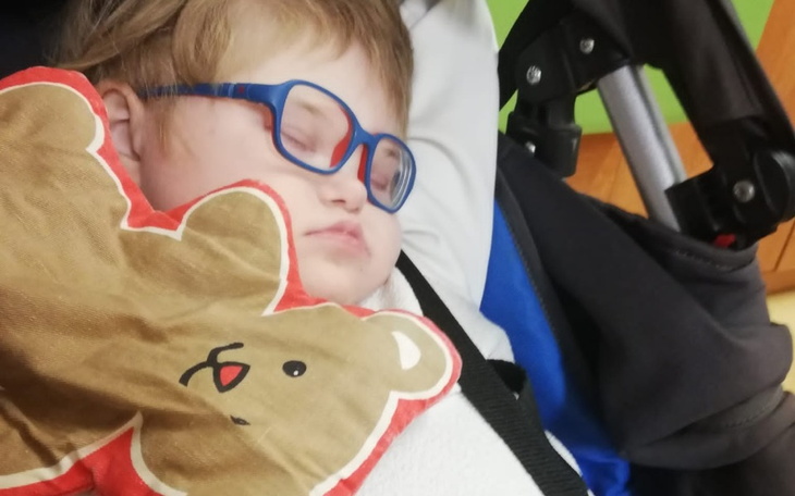 Małe dziecko śpiące w wózku, trzymające pluszowego misia.