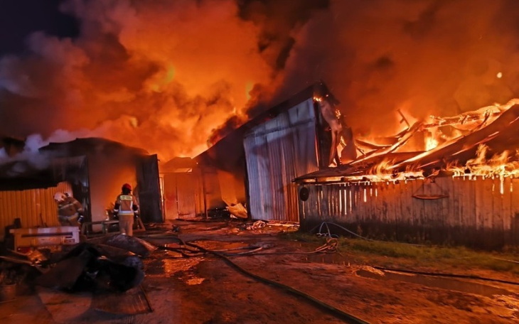 Pożar w nocy, strażacy walczą z ogniem w zniszczonym budynku.
