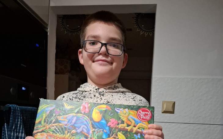 Chłopiec trzymający kolorowy obrazek z motywem zwierząt.