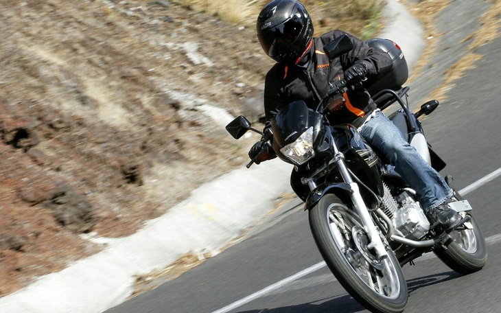 Motocyklista w kasku, jadący po krętej drodze.