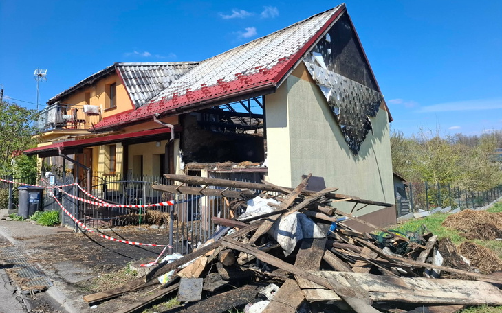 Zniszczony dom z uszkodzoną dachówką, otoczony gruzem.