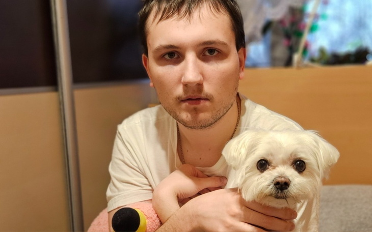 Mężczyzna trzymający małego psa, siedzący na kanapie.