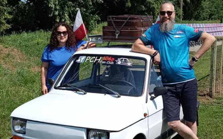 Para przy starym samochodzie z flagą Polski.