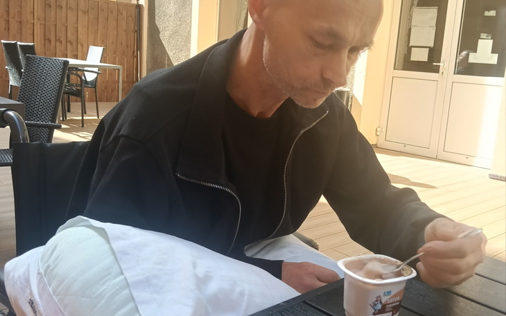 Mężczyzna jedzący lody na tarasie, skupiony na posiłku.