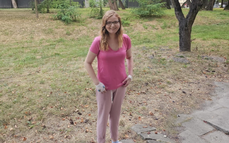 Uśmiechnięta dziewczyna w różowej koszulce na tle zieleni.