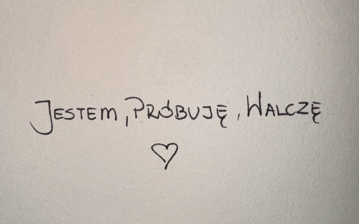 Napis na ścianie: 'Jestem, próbuję, walczę'.