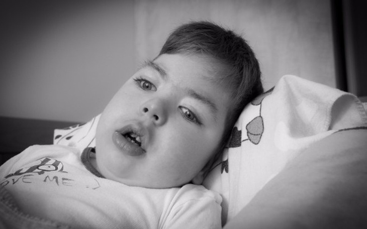 Chłopiec leżący na poduszce, z wyrazem twarzy pełnym zadumy.