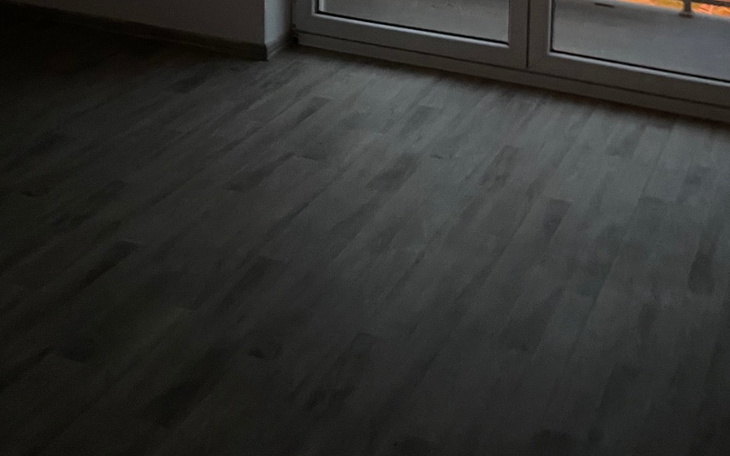 Ciemne pomieszczenie z widokiem na drzwi balkonowe.