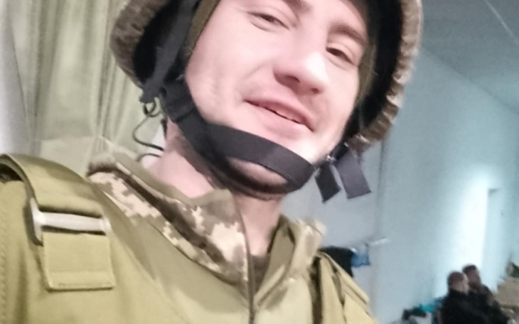 Mężczyzna w hełmie wojskowym, uśmiechający się do kamery.