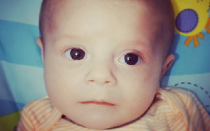 Noworodek z dużymi oczami, patrzący w obiektyw.