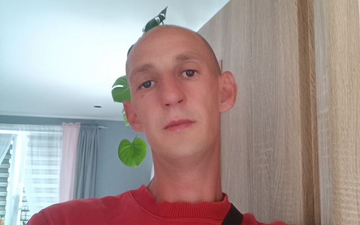 Mężczyzna z krótkimi włosami, patrzący w kamerę.