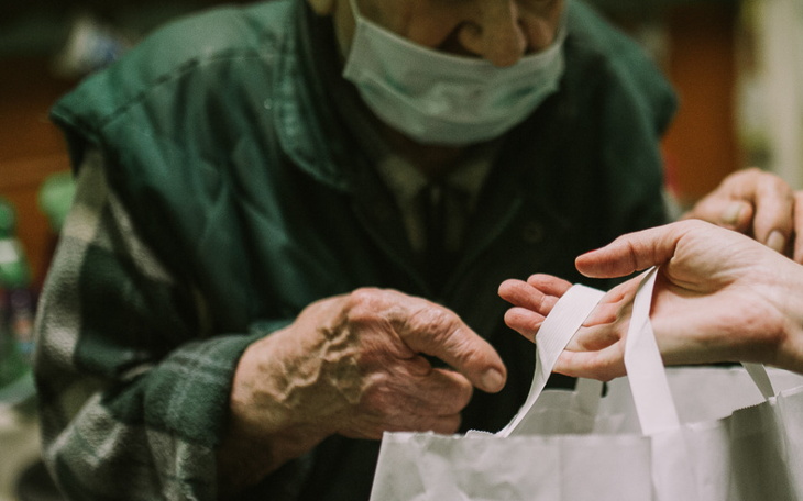 Ręce starszego mężczyzny przekazujące torbę z zakupami.