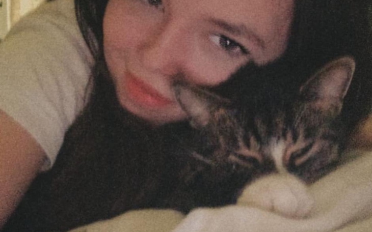 Młoda kobieta przytula kota, oboje wyglądają na szczęśliwych.