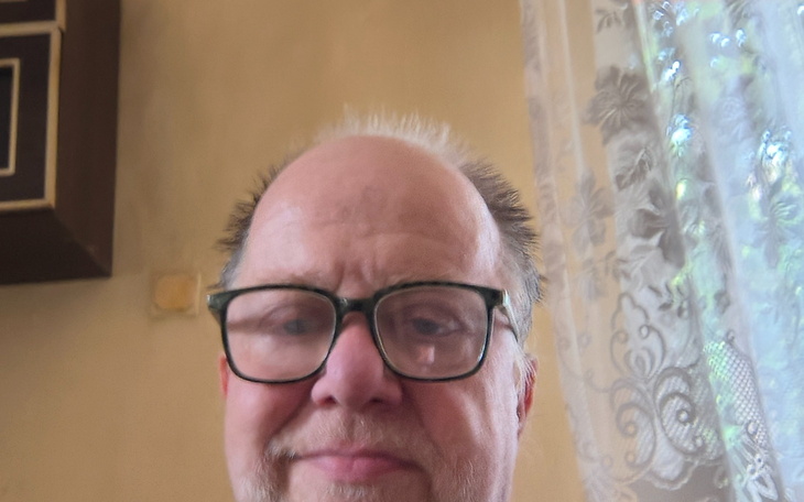 Mężczyzna w okularach, uśmiechający się do kamery.
