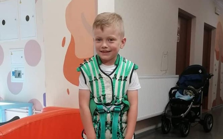 Chłopiec w specjalnym sprzęcie rehabilitacyjnym w szpitalu.