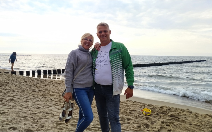 Para uśmiechniętych ludzi na plaży, cieszących się chwilą.