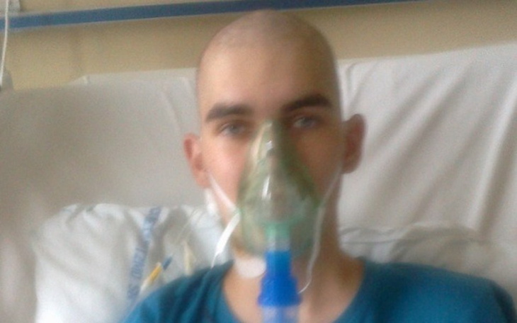 Młody mężczyzna w szpitalu z maską tlenową na twarzy.