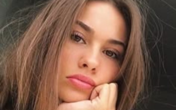 Młoda kobieta z zamyśloną miną, patrzy w dal.