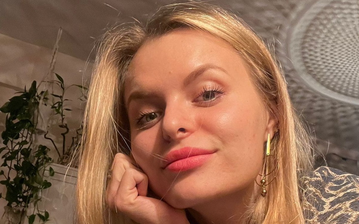 Kobieta z uśmiechem, pozująca w przytulnym wnętrzu.