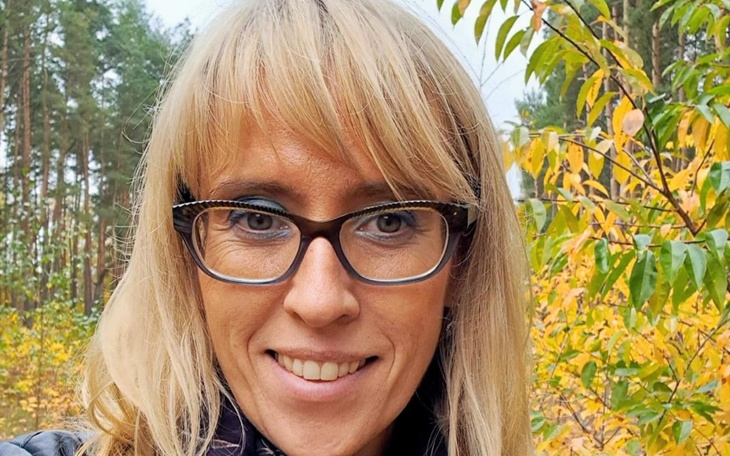 Kobieta w okularach na tle jesiennego lasu.