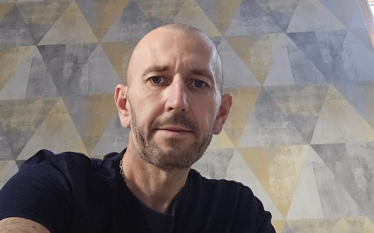 Mężczyzna robi sobie selfie, w tle geometryczna tapeta.