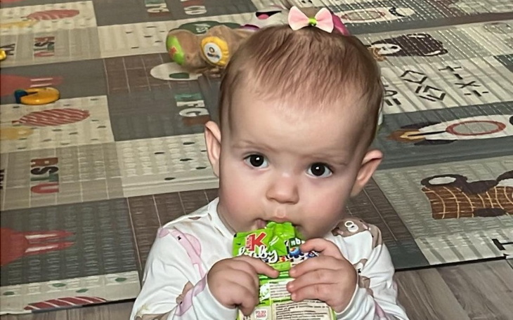 Mała dziewczynka trzymająca sok w opakowaniu, skupiona na zabawie.