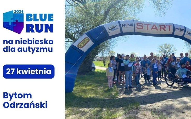 Grupa ludzi na biegu charytatywnym, z bramą startową w tle.