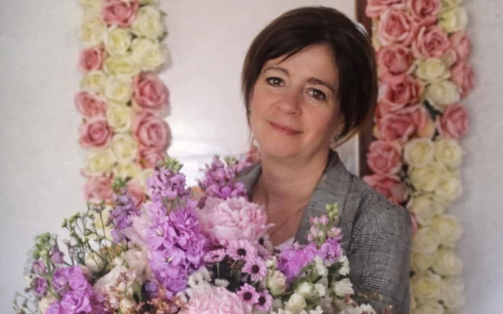 Kobieta z bukietem kwiatów, uśmiechająca się do kamery.