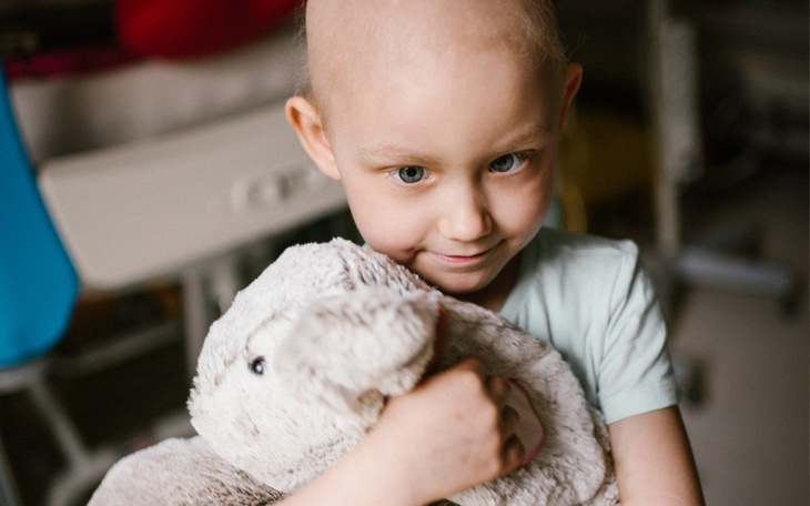 Mała dziewczynka z krótkimi włosami, trzymająca pluszowego królika.