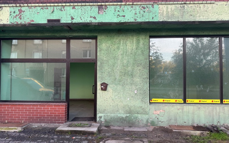 Zniszczona elewacja budynku z zielonymi ścianami.