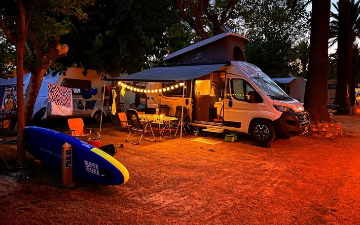 Przytulny kemping z oświetleniem i sprzętem do surfingu.