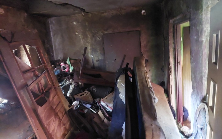 Zniszczony pokój po pożarze, z meblami w nieładzie.