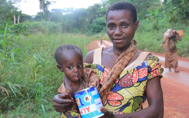 Kobieta trzymająca dziecko na rękach w otoczeniu natury.