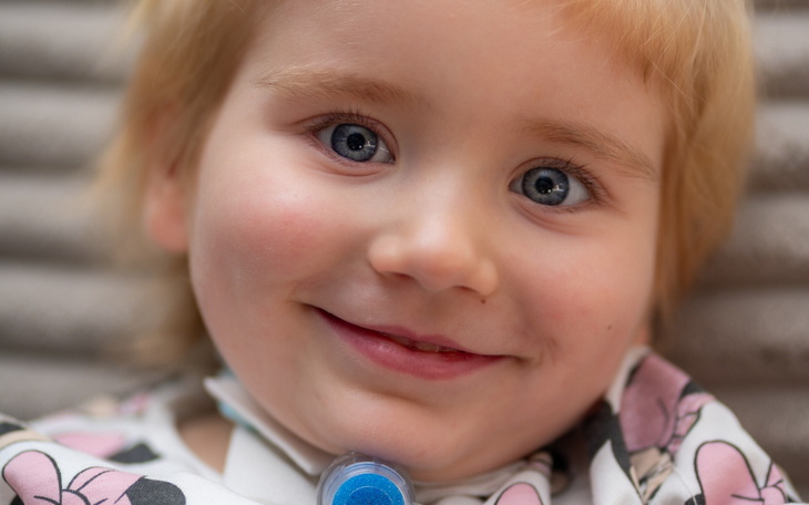 Uśmiechnięte dziecko z niebieskimi oczami.