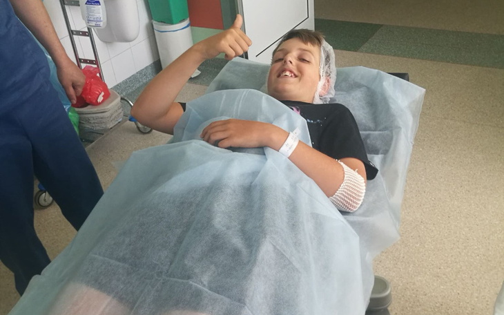 Chłopiec w szpitalu z uśmiechem i kciukiem w górę.