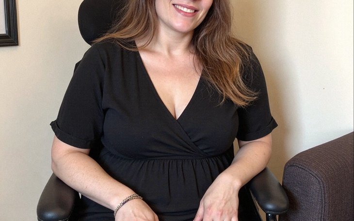 Uśmiechnięta kobieta siedząca na krześle biurowym.