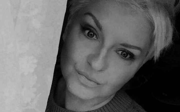 Portret kobiety z krótkimi włosami, uśmiechającej się do obiektywu.