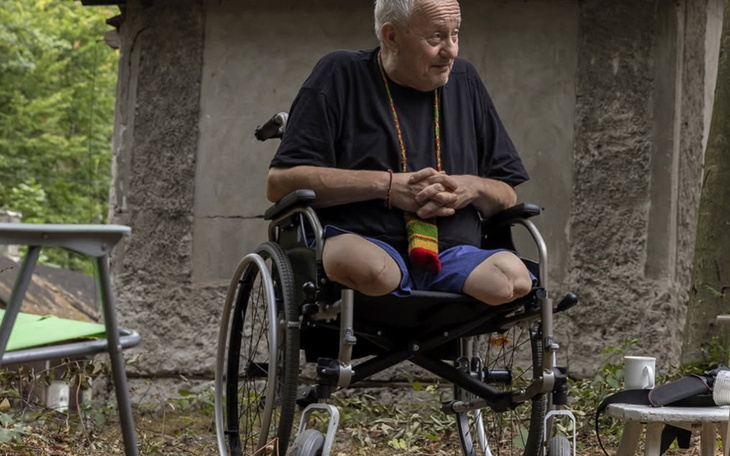 Mężczyzna na wózku inwalidzkim, siedzący w otoczeniu natury.